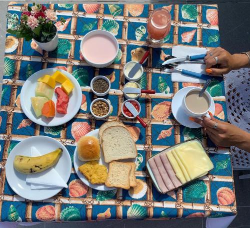 uma mesa coberta com pratos de alimentos e bebidas ao pequeno-almoço em Caminho das Pedras Búzios em Búzios