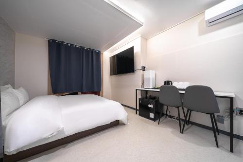 a bedroom with a bed and a desk with two chairs at Hotel Centro Stay in Incheon