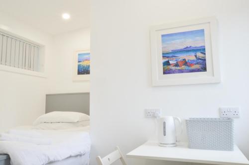 a white bedroom with a bed and a picture on the wall at Viewpoint East in Dunollie