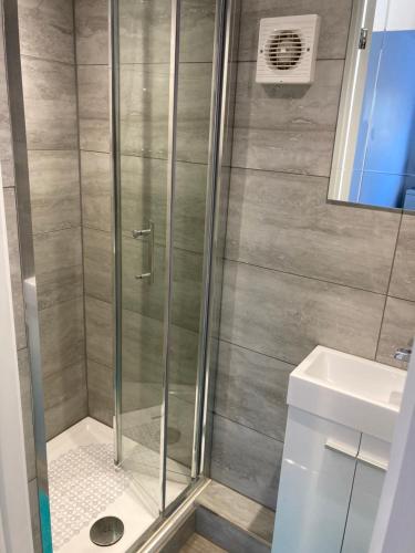 a shower with a glass door next to a sink at Watergall Lodge in Peterborough