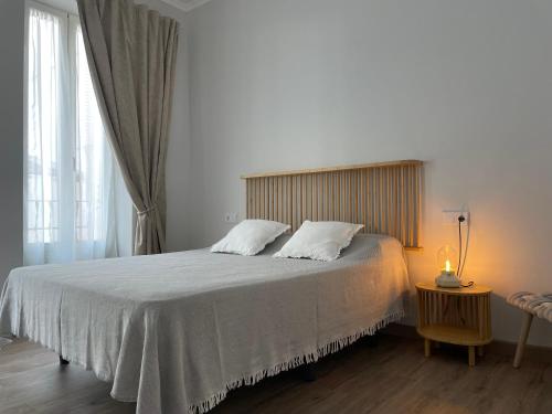 um quarto com uma cama com lençóis brancos e uma janela em Maison Sereine em Valência