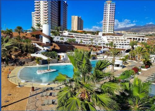 un complejo con piscina, palmeras y edificios en Sol apartment with amazing seaview, en Adeje