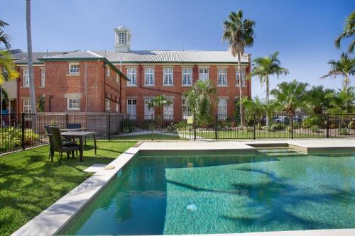 a pool in front of a building with a table and chairs at Quality Hotel Regent Rockhampton in Rockhampton