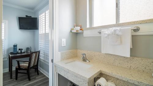 a bathroom with a sink and a desk with a chair at Greenleaf Hotel Long Beach Convention Center in Long Beach