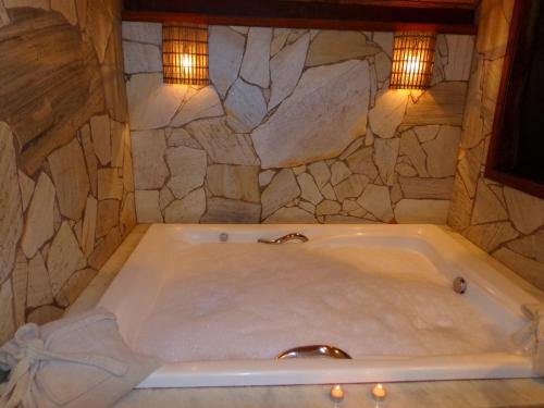 uma banheira num quarto com uma parede de pedra em pousada no caminho do escorrega em Visconde de Mauá