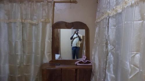 un homme prenant une photo de lui-même dans un miroir dans l'établissement Annex House For Rent, à Manjai Kunda
