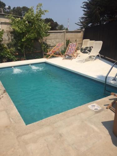 a swimming pool with two lawn chairs next to it at Casa isla Negra in Isla Negra