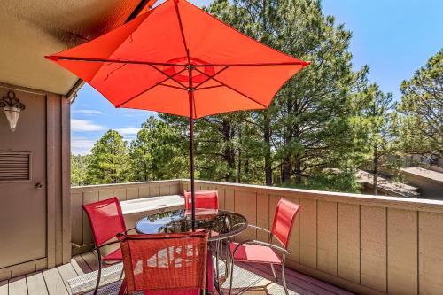 a table and chairs with a red umbrella on a balcony at Delightful 1 bdrm Country Club Retreat with Mt Elden Views! in Flagstaff