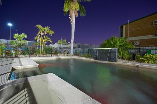 a swimming pool at night with a palm tree at Quality Hotel Regent Rockhampton in Rockhampton