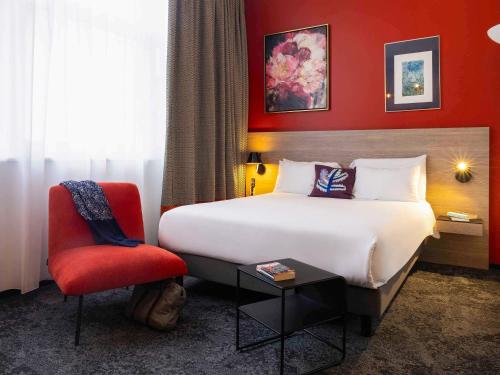 une chambre d'hôtel avec un lit et un mur rouge dans l'établissement Mercure Hotel Forbach Centre de Loisirs, à Forbach