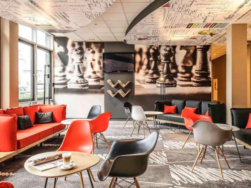 a waiting room with red and black chairs and tables at ibis Köln Messe in Cologne