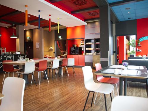 a restaurant with white chairs and tables and red walls at ibis Köln Messe in Cologne