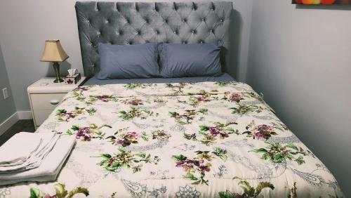 un letto con piumone floreale e testiera blu di Olive Place a Saskatoon