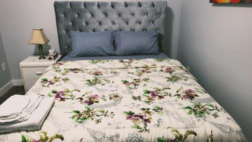 a bed with a floral comforter and a blue headboard at Olive Place in Saskatoon