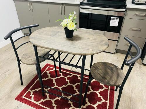 a wooden table with two chairs and a vase of flowers on it at Olive Place in Saskatoon