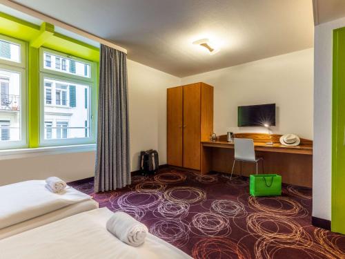 a hotel room with a bed and a desk at ibis Styles Luzern in Lucerne