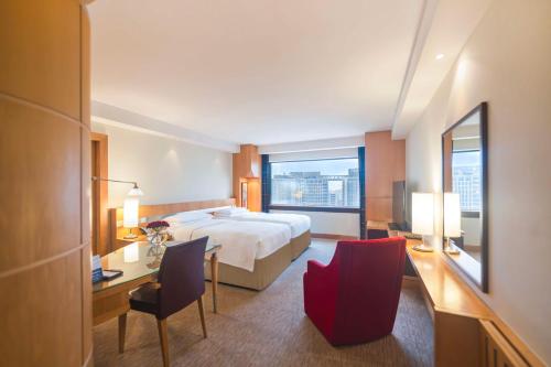 Cette chambre comprend un lit, un bureau et des chaises. dans l'établissement Hyatt Regency Dubai - Corniche, à Dubaï