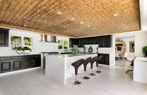 a kitchen with black cabinets and a white island with stools at Luxury Bel Air Villa Heated Pool Panoramic Views 6 Bedrooms in Los Angeles