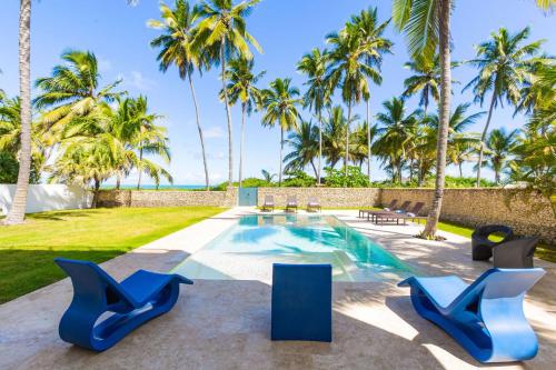 a resort pool with blue chairs and palm trees at Villa Blue Amber Cabarete in Cabarete