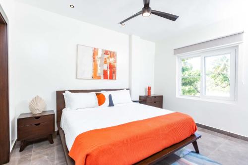 a white bedroom with a bed with an orange blanket at Villa Blue Amber Cabarete in Cabarete