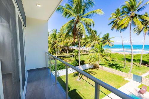 a balcony with a view of the beach and palm trees at Villa Blue Amber Cabarete in Cabarete