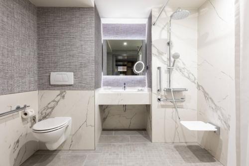 a bathroom with a toilet and a sink and a mirror at Paris Marriott Charles de Gaulle Airport Hotel in Roissy-en-France