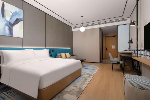 a hotel room with a bed and a desk at Hilton Garden Inn Shenzhen Guangming Hongqiao Park in Shenzhen