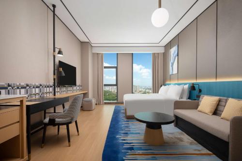 a hotel room with a bed and a couch at Hilton Garden Inn Shenzhen Guangming Hongqiao Park in Shenzhen