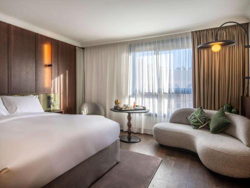 ブリュッセルにあるLe Louise Hotel Brussels - MGallery Collectionのベッド、ソファ、窓が備わるホテルルームです。