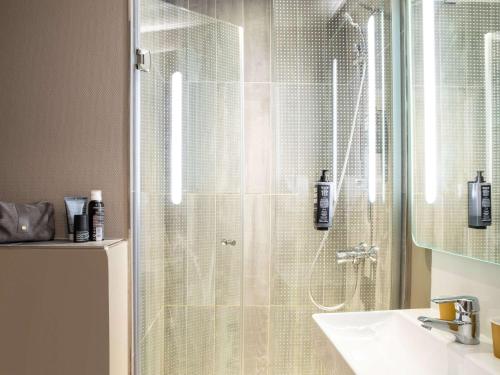 y baño con ducha acristalada y lavamanos. en ibis Paris Ornano Montmartre Nord 18ème en París