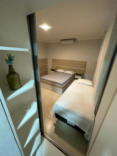 a small bedroom with two beds and a mirror at Casa Mariscal perto do mar in Bombinhas