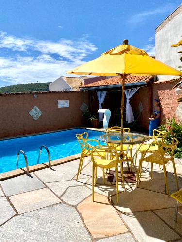 a yellow umbrella and chairs next to a swimming pool at Vila Vitória Pousada in Pirenópolis