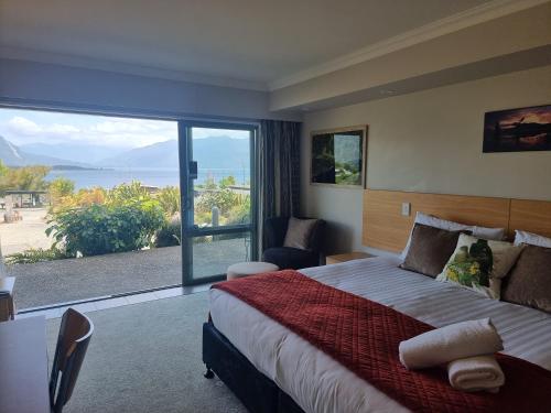 a bedroom with a large bed and a large window at Hotel Lake Brunner in Moana