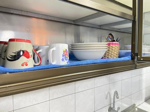 Udon House في أودون ثاني: رف عليه أكواب وأوعية في مطبخ