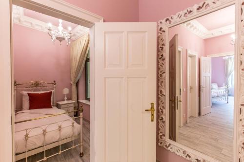 a bedroom with a mirror and pink walls at Grande Albergo Giancarlo in Weimar