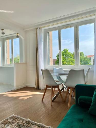 uma sala de estar com uma mesa, cadeiras e janelas em 2 bedrooms, 15min from Paris, free parking em Deuil-la-Barre