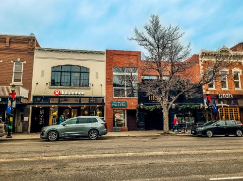 eine Stadtstraße mit Autos, die vor den Gebäuden geparkt sind in der Unterkunft Treasure State Hostel in Bozeman