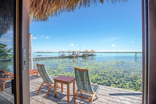 a patio with two chairs and a table and a pier at Yayum Bacalar in Bacalar