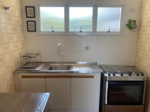 a kitchen with a sink and a stove and a window at Guarujá Pé na Areia in Guarujá