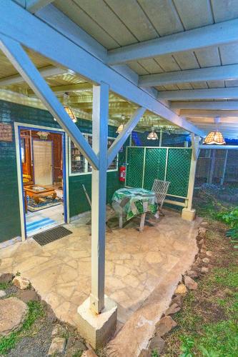 a covered patio with a table and a table at Heimanarii's Lodge - Fare Miti in Haapiti