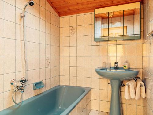 y baño con bañera azul y lavamanos. en Quiet holiday apartment near Klopeinersee, en Gallizien