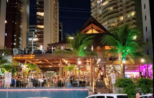 a restaurant with people sitting outside of it at night at Apartamento Condominio Emilio Hinko - Beira Mar in Fortaleza