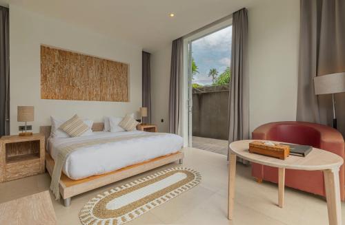 スミニャックにあるTaman Mesari Luxury Villas-Seminyakのベッドルーム1室(ベッド1台、テーブル、椅子付)