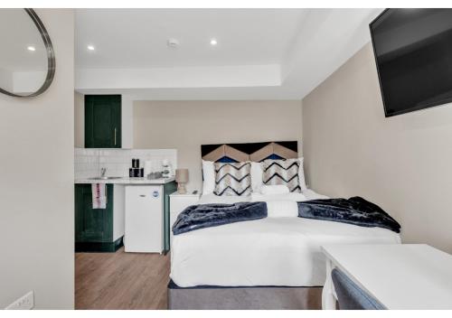 a bedroom with a large white bed and a kitchen at Stay & Explore: Convenient Studio - Prime Location in London