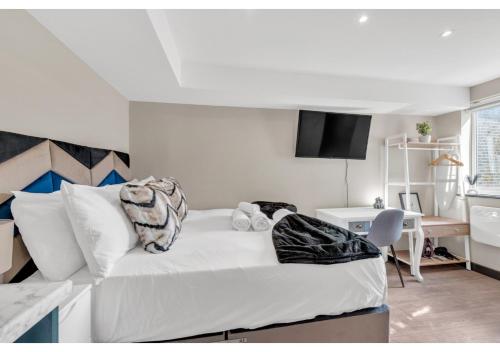 sypialnia z białym łóżkiem, biurkiem i stołem w obiekcie Stay & Explore: Convenient Studio - Prime Location w Londynie