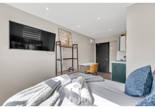 Schlafzimmer mit einem Bett und einem Flachbild-TV in der Unterkunft A Place to Dream: Airy Studio in Serene Locale in London