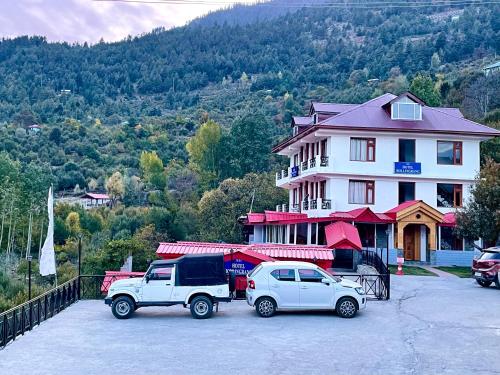 two vehicles parked in a parking lot in front of a building at Hotel Rollingrang in Kalpa