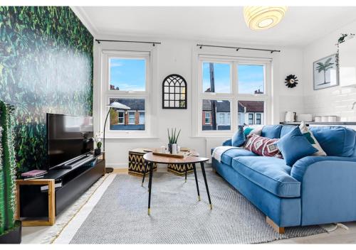 a living room with a blue couch and a tv at Earth Tones & Greenery: 4BR Flat Sleeps 8 in London