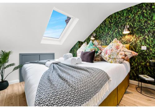 Schlafzimmer mit einem Bett und einem Fenster in der Unterkunft Earth Tones & Greenery: 4BR Flat Sleeps 8 in London
