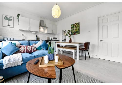 a living room with a blue couch and a table at Earth Tones & Greenery: 4BR Flat Sleeps 8 in London